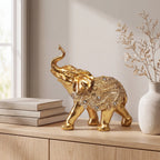 Escultura elefante da sorte dourado em mármore claro com planta tropical ao fundo