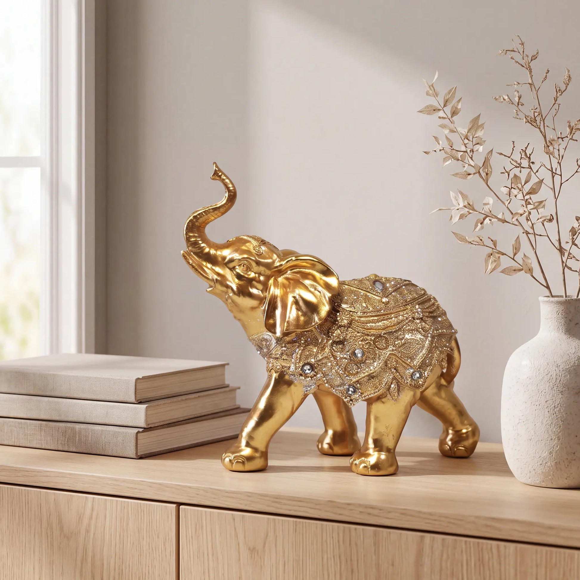 Escultura elefante da sorte dourado em mármore claro com planta tropical ao fundo