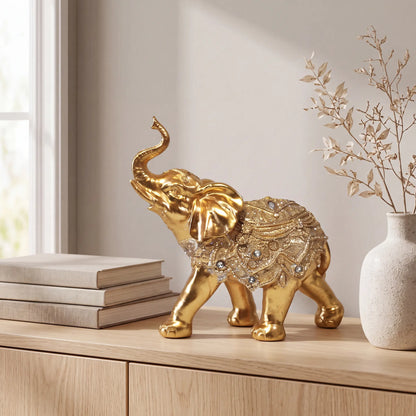 Escultura elefante da sorte dourado em mármore claro com planta tropical ao fundo