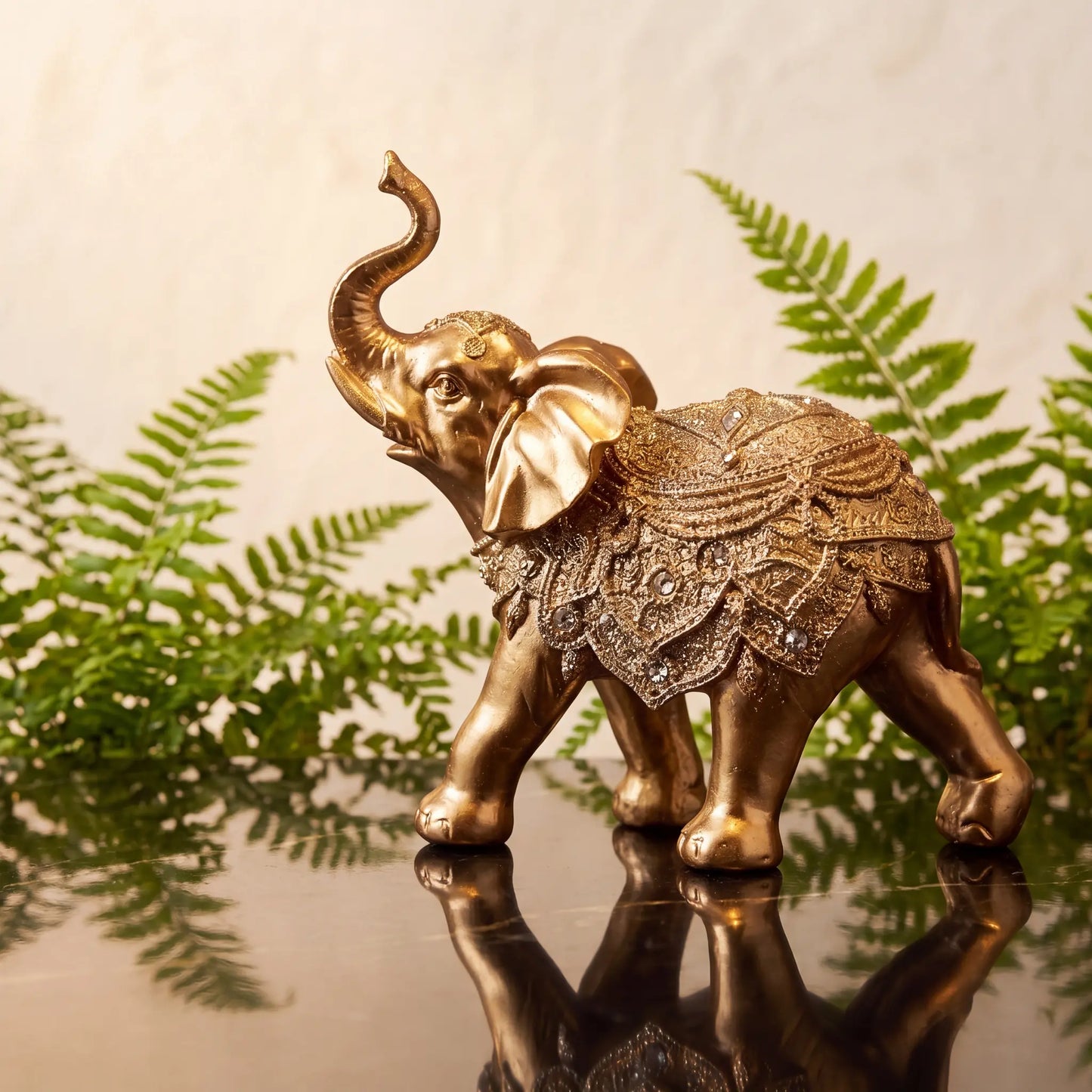 Escultura elefante da sorte dourado sobre console com samambaia ao fundo