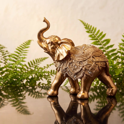 Escultura elefante da sorte dourado sobre console com samambaia ao fundo