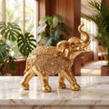 Escultura elefante da sorte dourado em aparador de mármore com planta tropical e luz quente