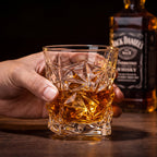 Copo de vidro lapidado geométrico Prisma 290ml com whisky segurado por mão masculina em bar escuro