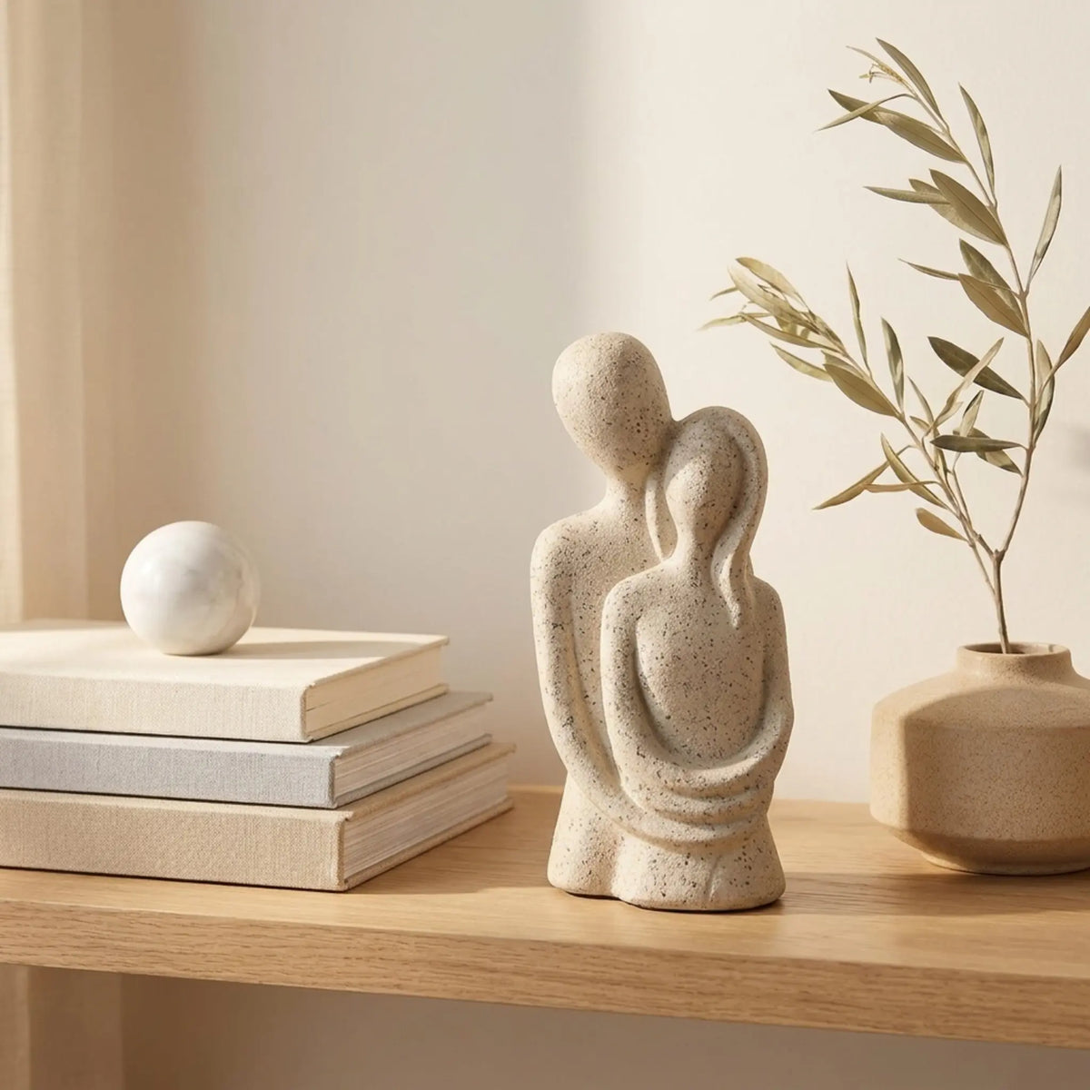 Escultura casal abraçado em estante de madeira com livros e vaso