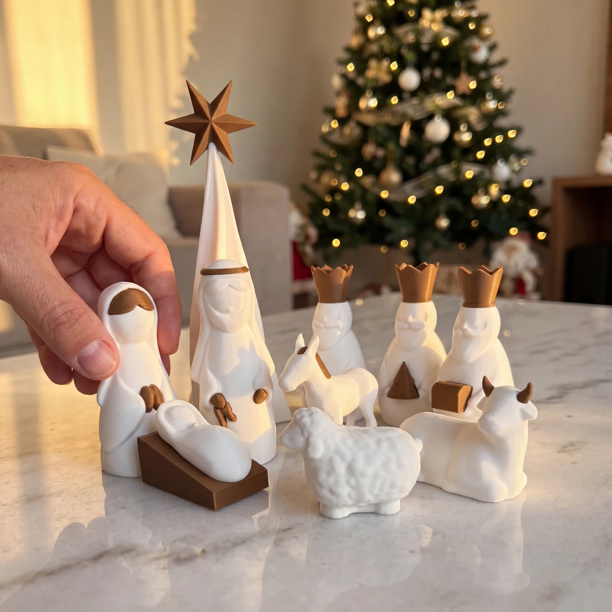 Presépio Sagrada Família 3D com mão posicionando a figura de Maria sobre mármore com árvore de Natal ao fundo