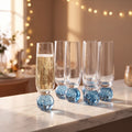 Kit 6 taças champagne vidro bubble azul com base esférica em balcão de mármore com luz dourada e luzinhas ao fundo