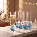 Kit 6 taças champagne vidro bubble azul com base esférica em balcão de mármore com luz dourada e luzinhas ao fundo