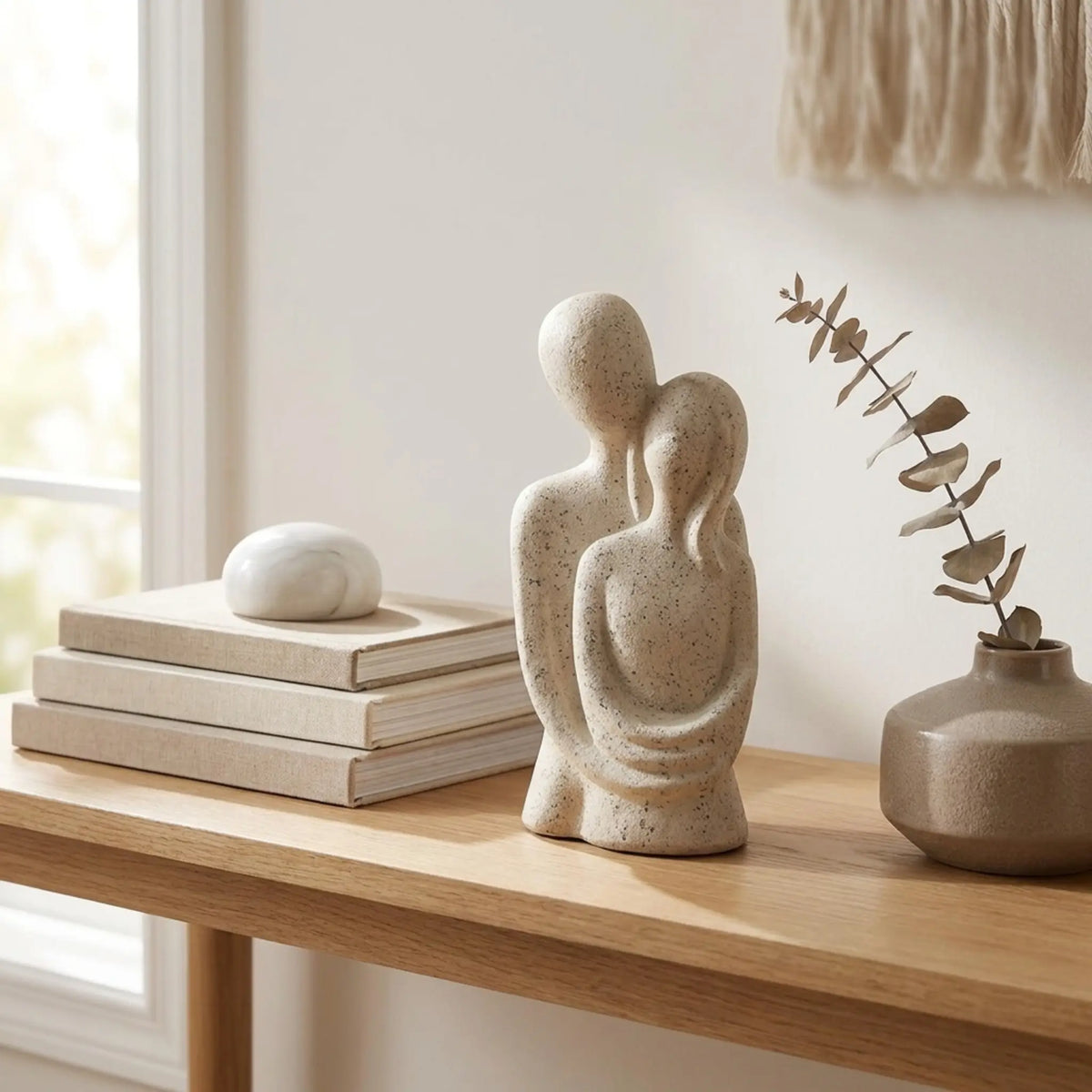 Escultura casal abraçado em console com vaso e ramo seco decorativo