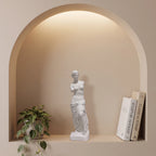 Escultura Vênus de Milo em gesso cru dentro de nicho em arco com iluminação indireta e planta pendente