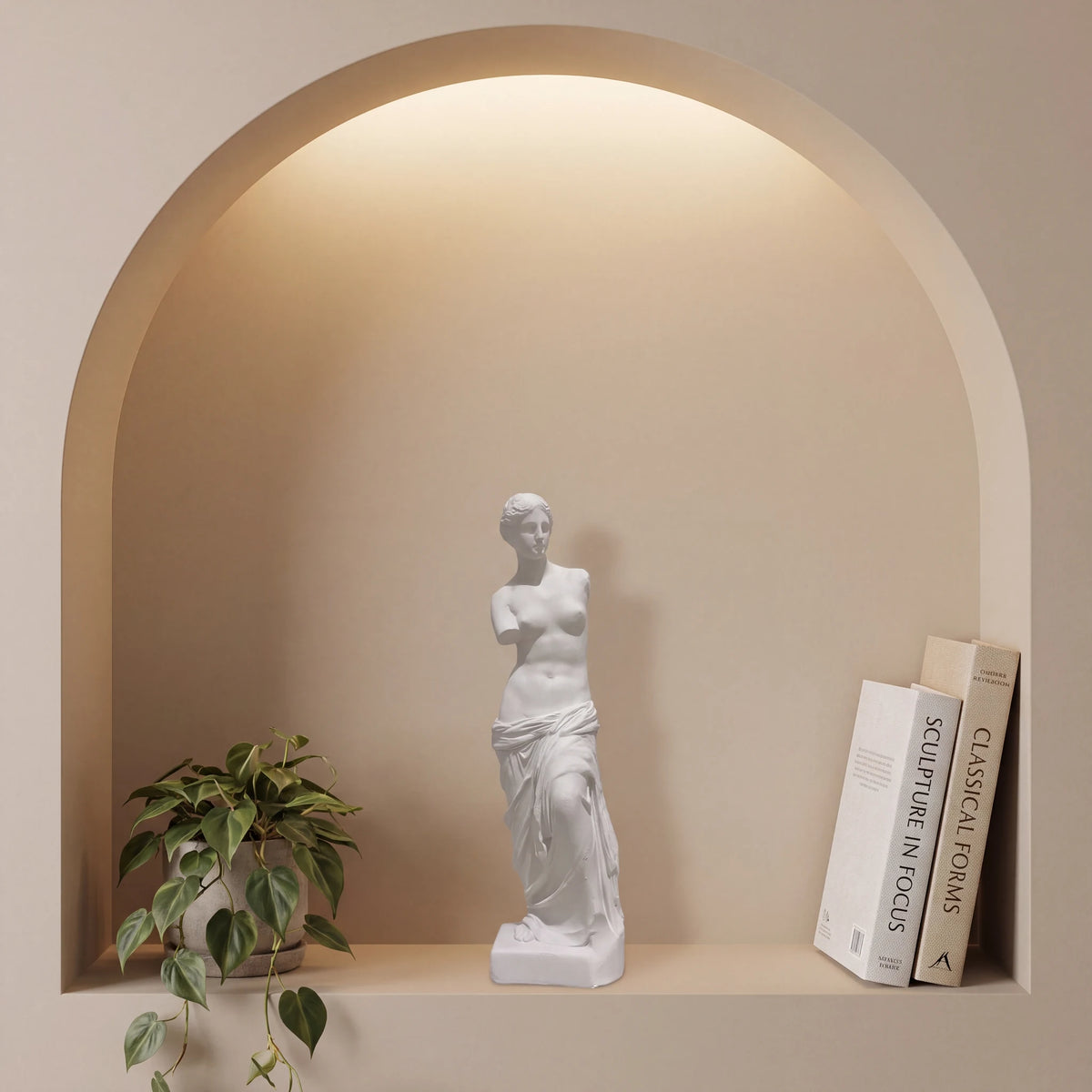 Escultura Vênus de Milo em gesso cru dentro de nicho em arco com iluminação indireta e planta pendente