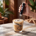 Mixer elétrico portátil batendo cappuccino com espuma cremosa sobre bancada de mármore