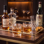 Par de copos de vidro lapidado Prisma com whisky em home bar com garrafas premium e laranjas secas