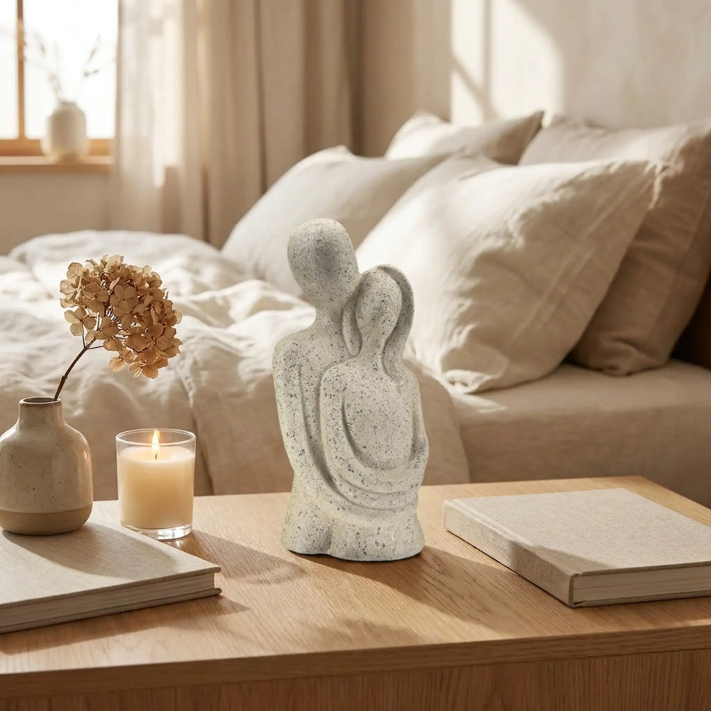 Escultura casal abraçado em quarto aconchegante com vela e flor seca