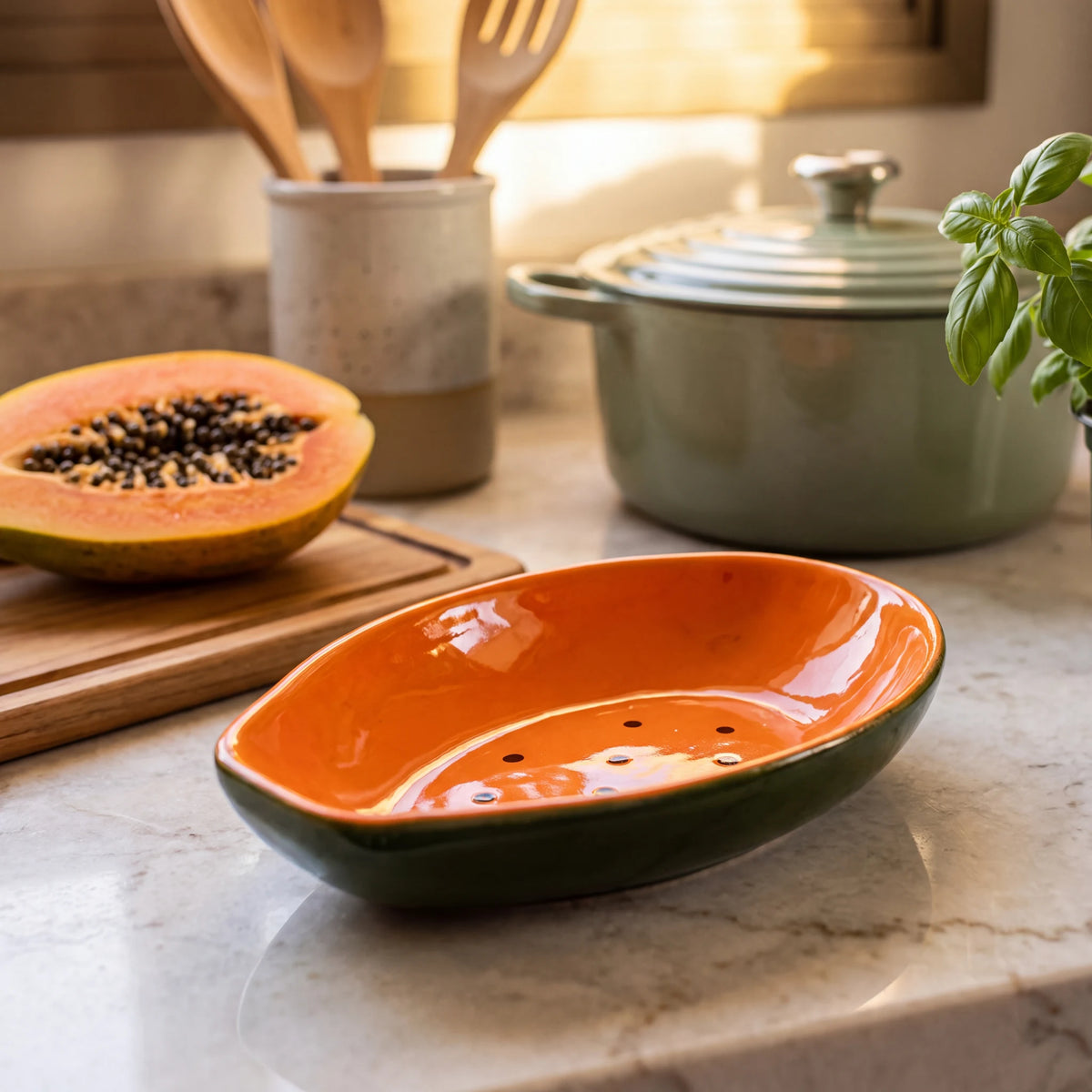 Bowl Tropicália Mamão em cerâmica verde e laranja close-up em bancada de mármore com utensílios ao fundo