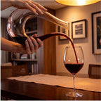 	Decanter Sinuoso em cristal sendo segurado por mãos femininas servindo vinho tinto em taça em sala de estar