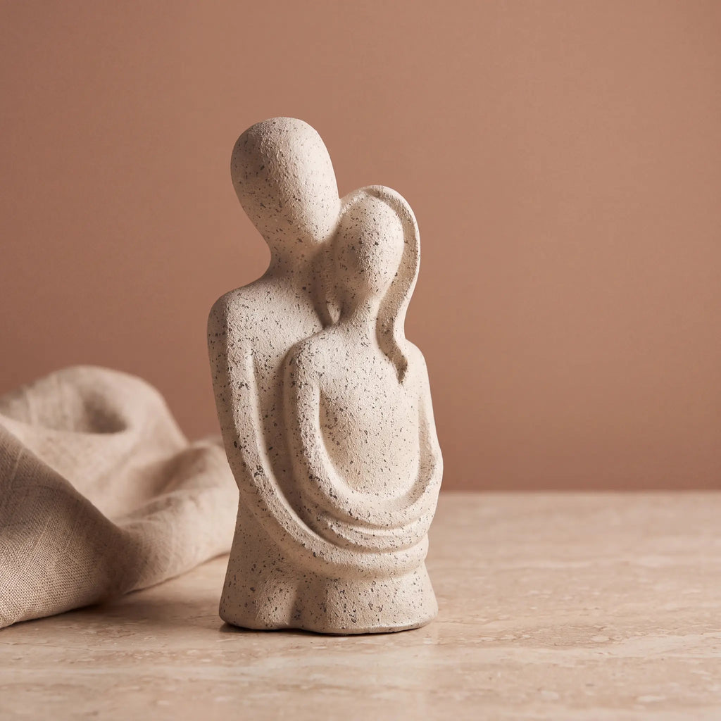 Escultura casal abraçado com fundo terracota e tecido de linho