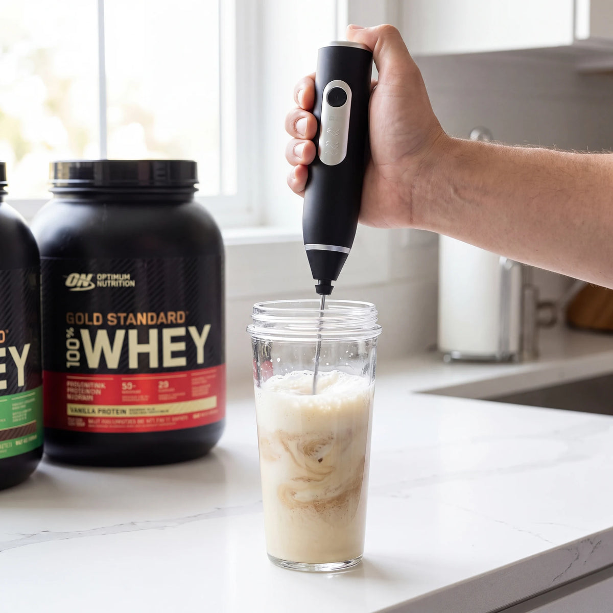 Mixer elétrico portátil misturando whey protein em coqueteleira de vidro