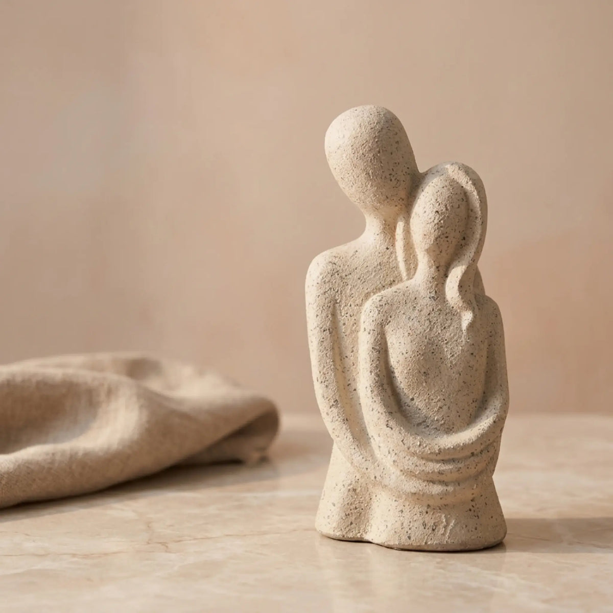 Escultura casal abraçado sobre superfície de mármore com linho