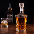 Licoreira de vidro lapidado Âmbar em close com whisky dourado, reflexos no vidro facetado, fundo escuro
