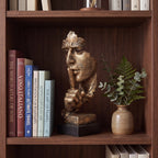 Escultura decorativa Silêncio e Paz dourada em estante de madeira com livros e vaso de eucalipto