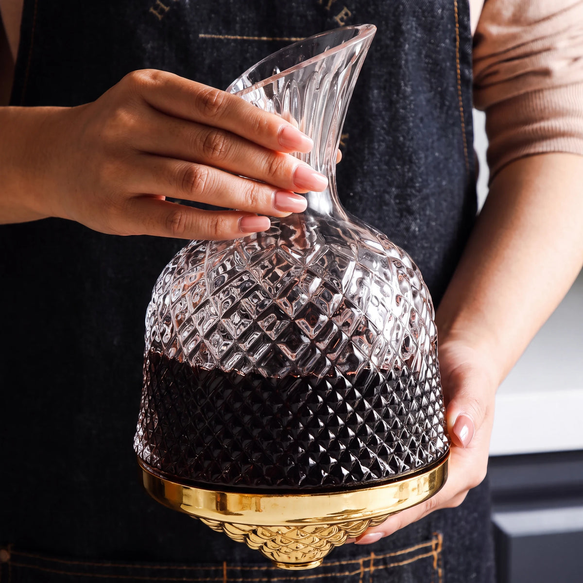 Decanter Vórtice cheio de vinho tinto segurado com as duas mãos, vidro lapidado