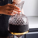 Decanter Vórtice cheio de vinho tinto segurado pelo gargalo, lapidação em diamante