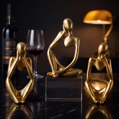 Kit 3 esculturas O Pensador douradas em ambiente de bar com garrafa e taça de vinho